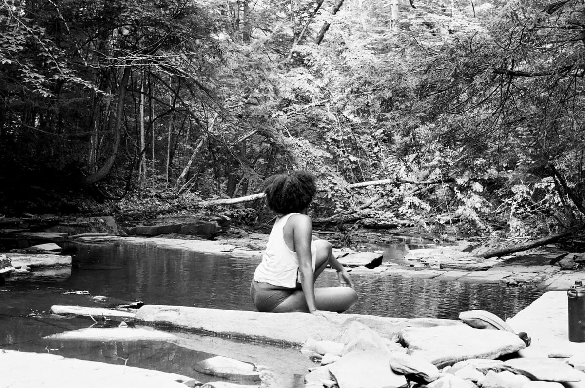 woman on rock looking at pond sustainable cadences